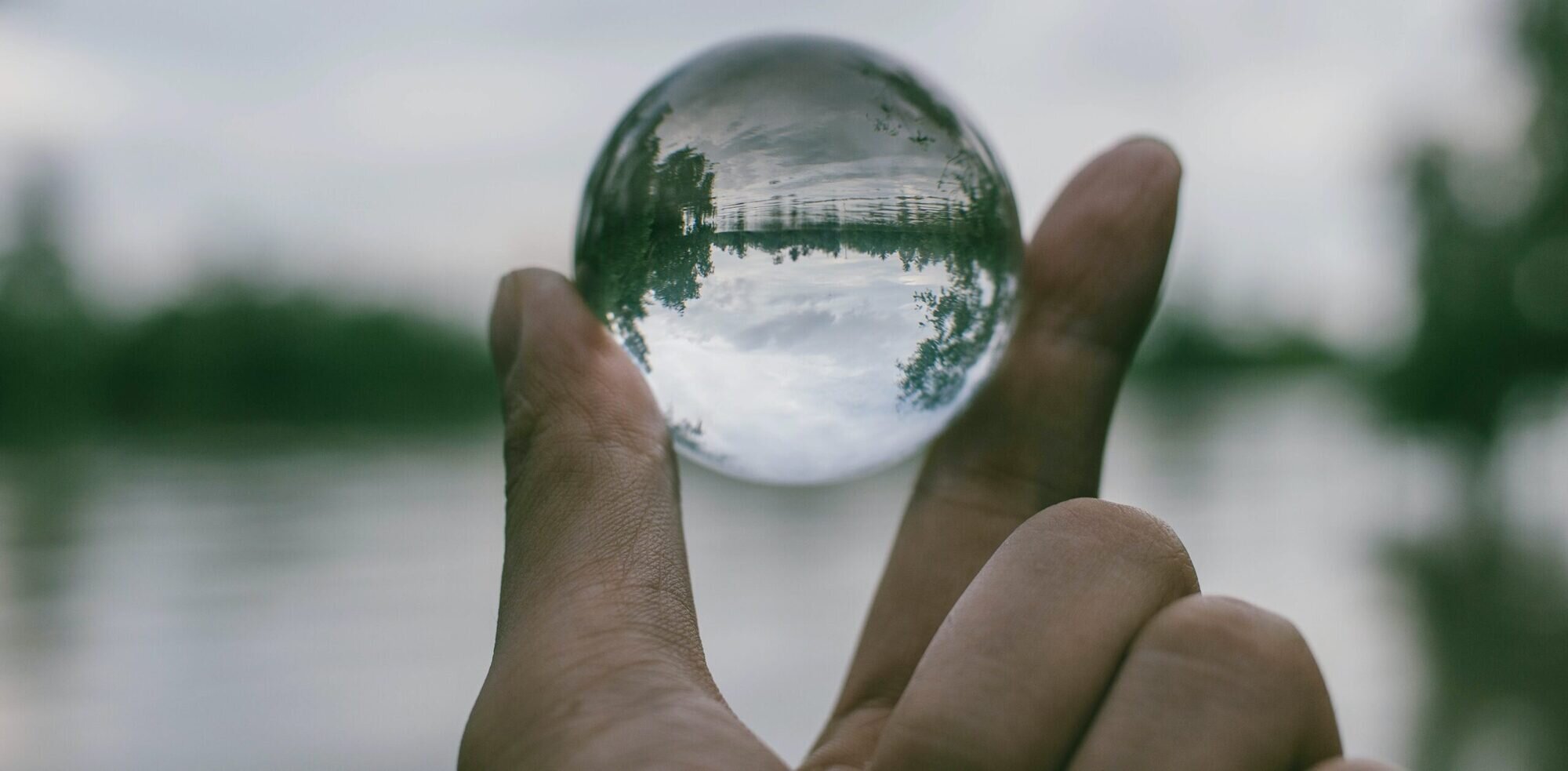 Landscape with a hand holding a glass sphere